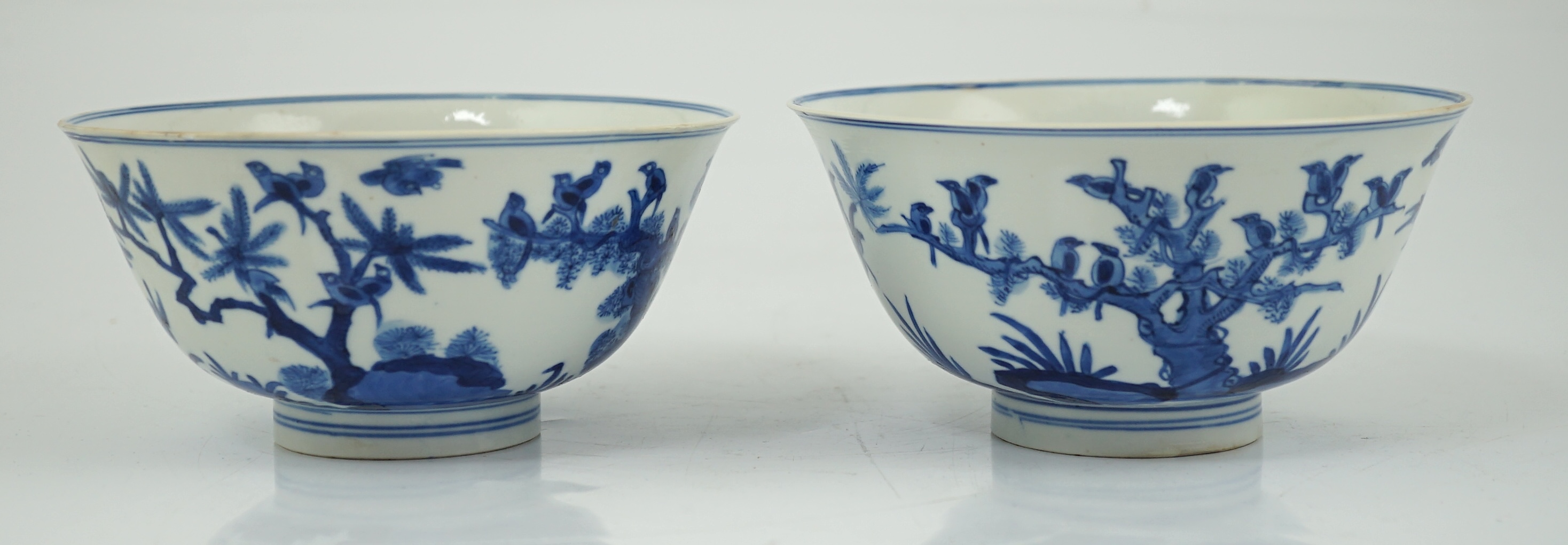 A near pair of Chinese blue and white ‘birds’ bowls, Kangxi period, one bowl restored